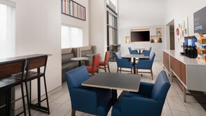 A modern cafe with seating arrangements, a coffee bar, and a flat-screen TV. - Holiday Inn Express & Suites Olive Branch by IHG (Olive Branch)