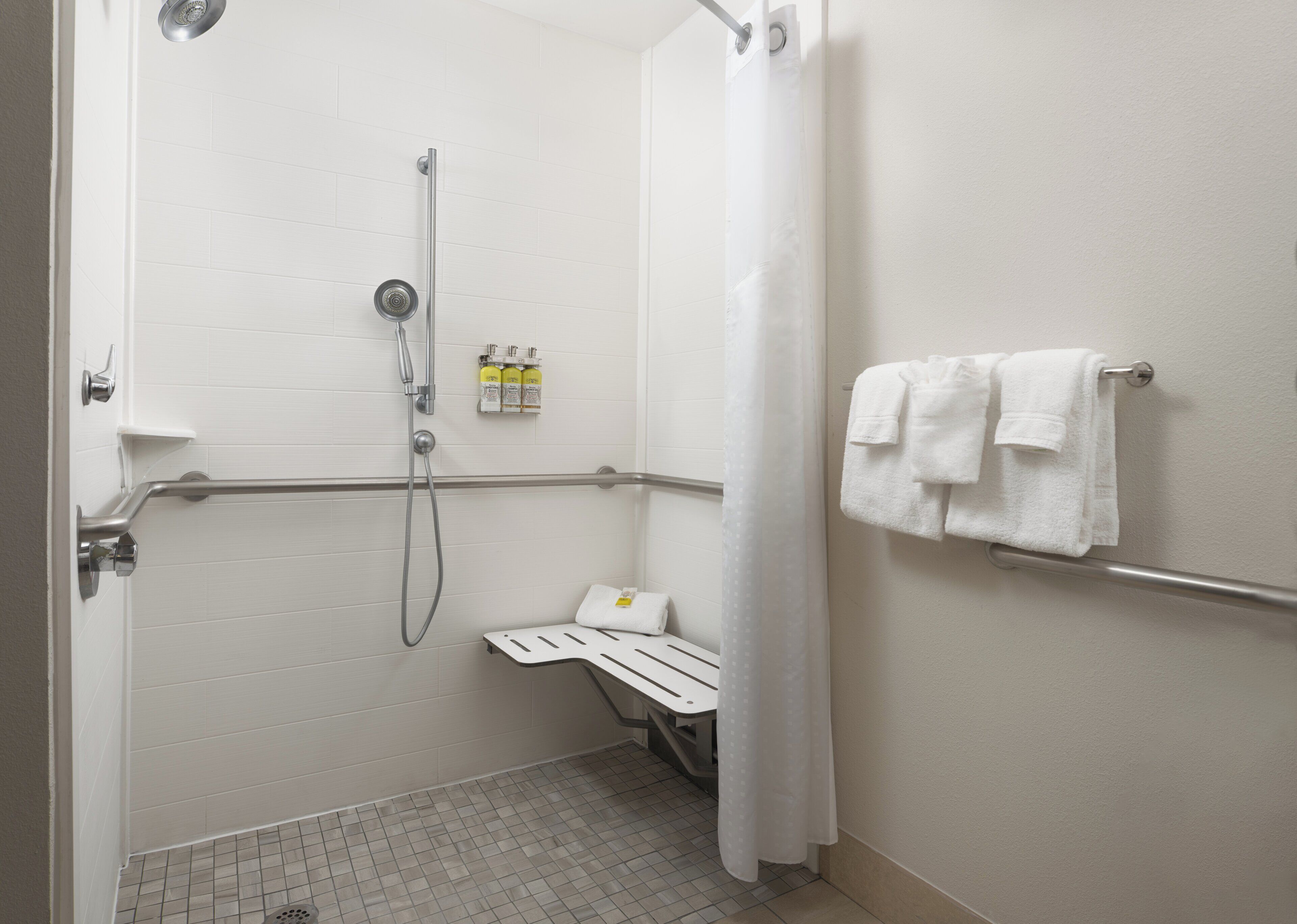 Un baño con ducha, un perchero para toallas y un banco pequeño.