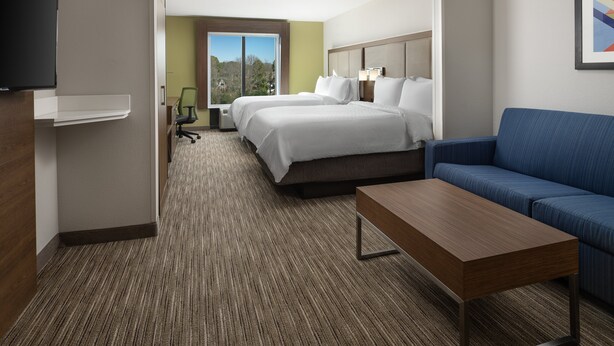 A hotel room with a bed, a sofa, a TV, a desk, and a window with a view. - Holiday Inn Express & Suites Olive Branch by IHG (Olive Branch)