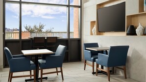 A modern dining area with large windows, a flat-screen TV, and blue upholstered chairs. - Holiday Inn Express & Suites Olive Branch by IHG (Olive Branch)