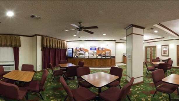 A hotel lobby with multiple tables and chairs, a reception desk, and a ceiling fan. - Holiday Inn Express & Suites Plainview by IHG (Plainview)
