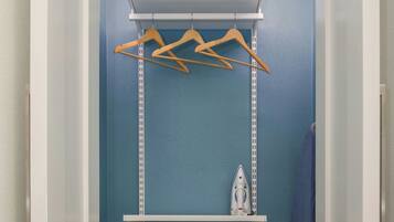 A walk-in closet with a blue wall, white shelving, and a hanging rod.