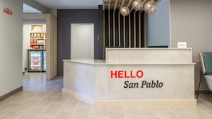 A reception desk with a 'HELLO San Pablo' sign, a patterned wall, and a refrigerator with snacks. - TownePlace Suites by Marriott San Pablo (San Pablo)
