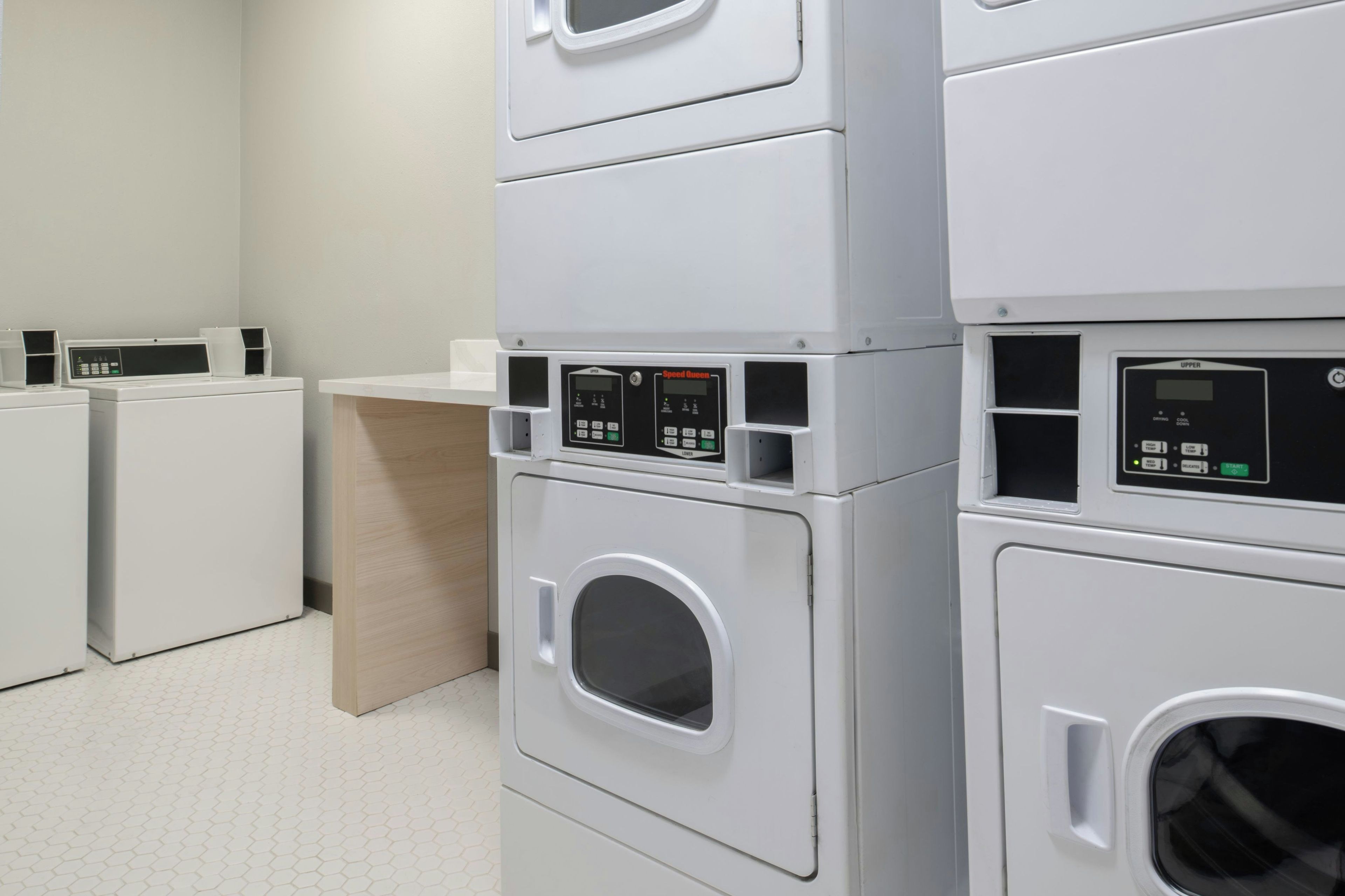A laundry facility with multiple stacked washing machines and dryers.
