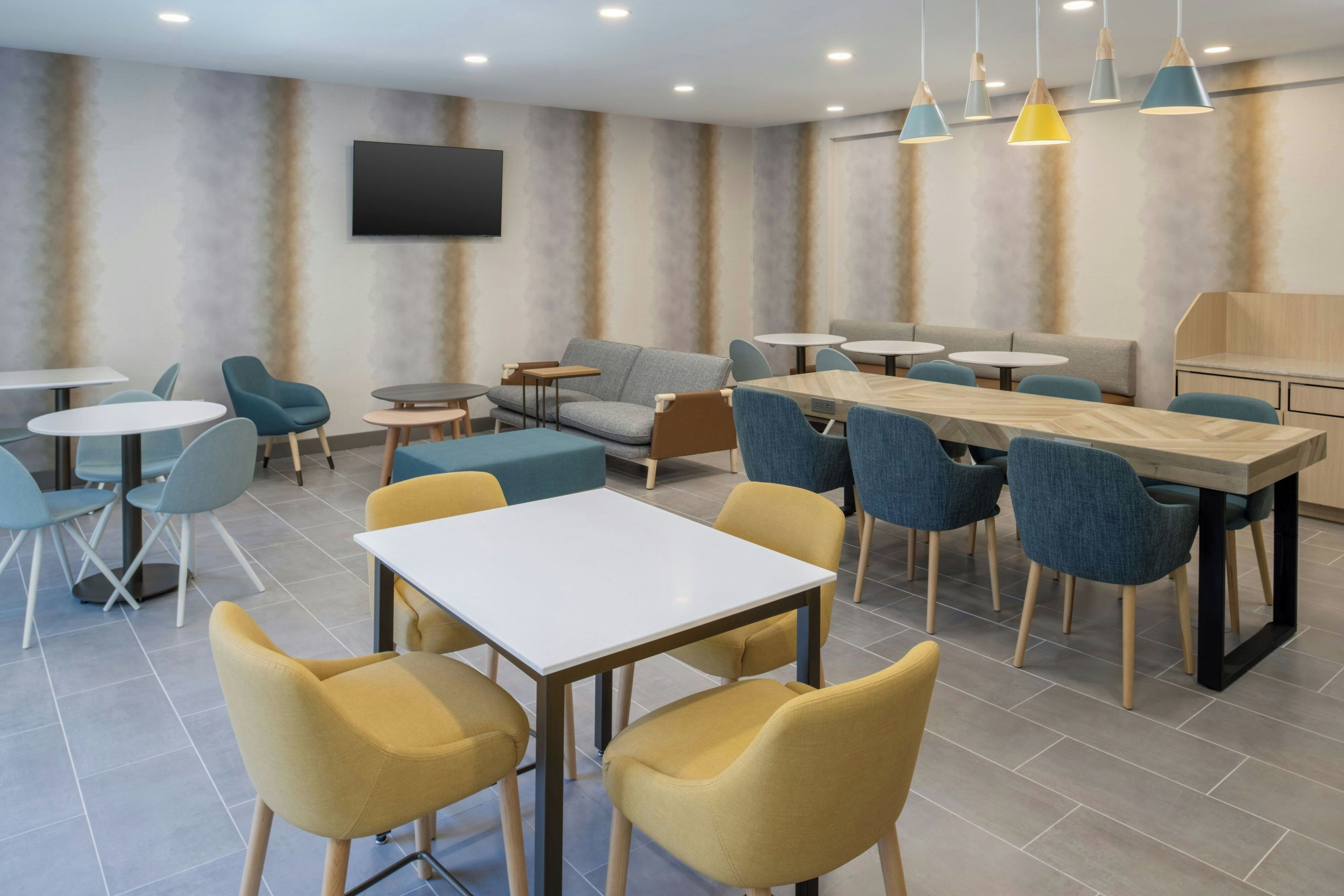 Un área de lounge moderna con diversas opciones de asientos, incluyendo sofás, sillones y mesas.