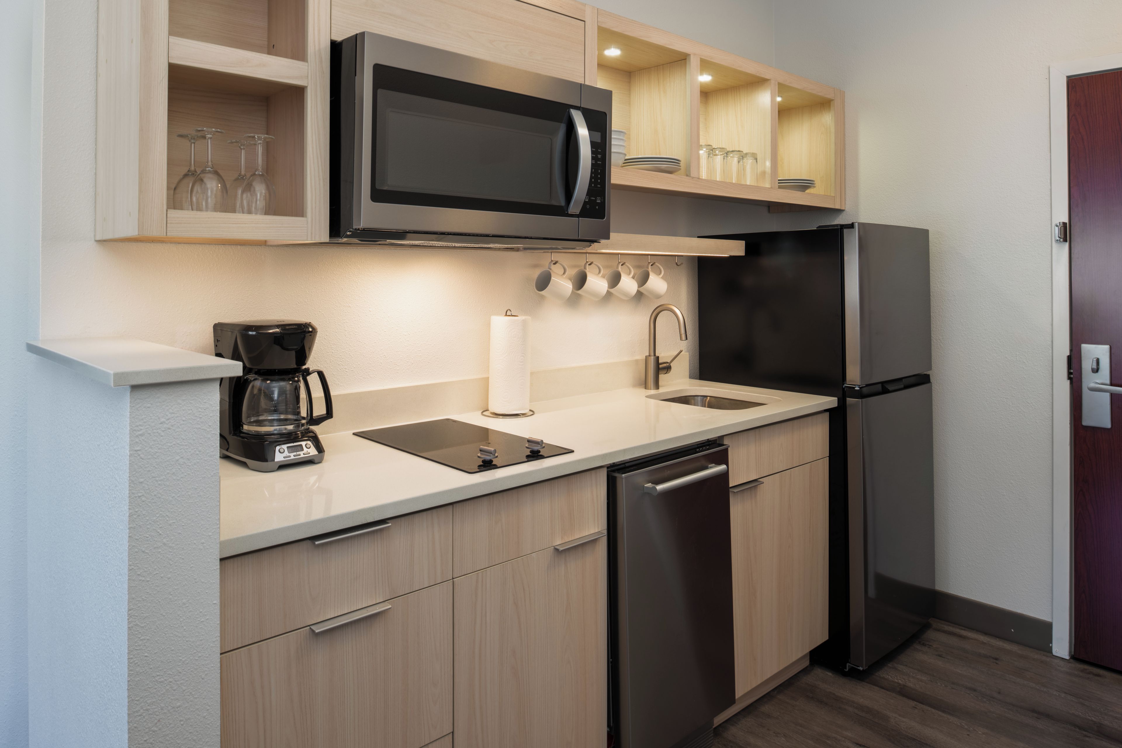A compact kitchen with a microwave, coffee maker, sink, and dishwasher.