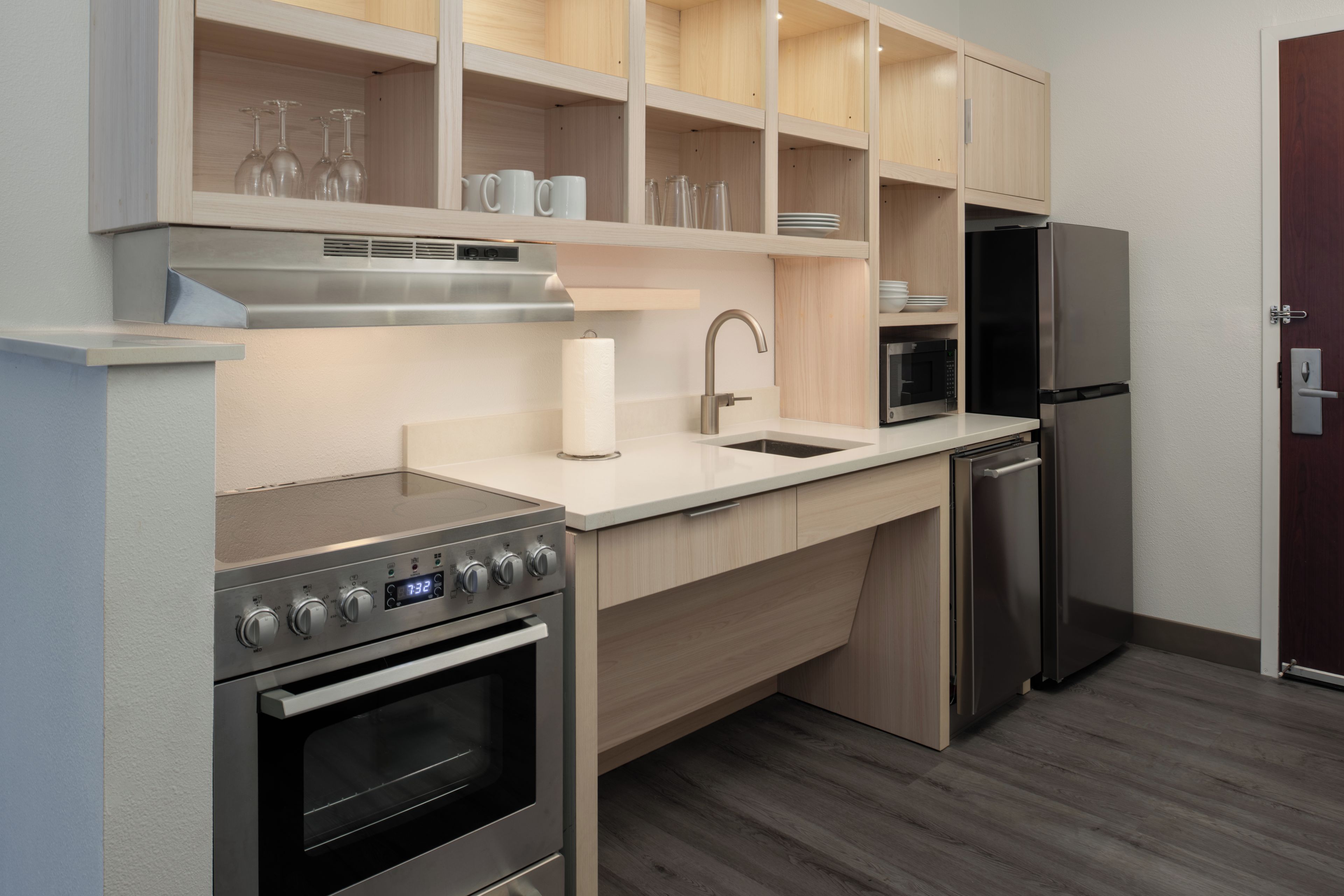 A modern kitchen with stainless steel appliances, wooden cabinets, and a built-in microwave.