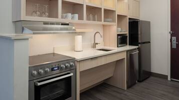 A modern kitchen with stainless steel appliances, wooden cabinets, and a built-in microwave.