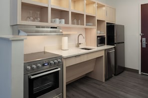 Une cuisine moderne dotée d’appareils électroménagers en acier inoxydable, de meubles en bois et d’un four à micro-ondes encastré.