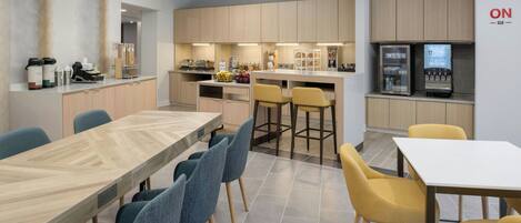 A modern kitchen with wooden cabinets, a central island, bar stools, and a refrigerator.