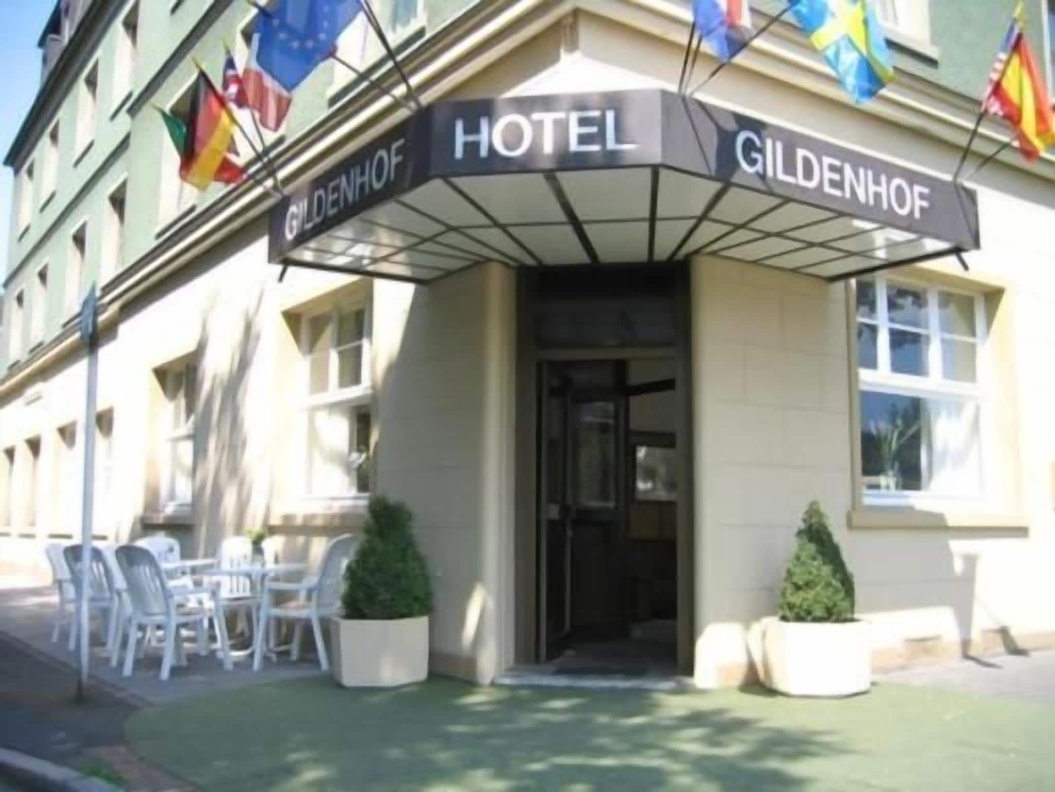 Ein Hotel Eingang mit einem Schild, das 'GILDENHOF HOTEL' zeigt, und Flaggen darüber.