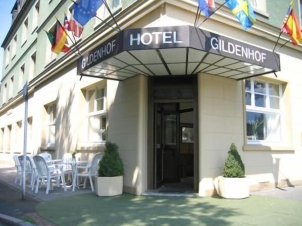 Entrada de un hotel con un cartel que dice 'GILDENHOF HOTEL' y banderas arriba.