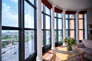 A room with large windows, a sofa, a table, and a vase of flowers. - METROPOL HOTEL Yerevan (Yerevan)