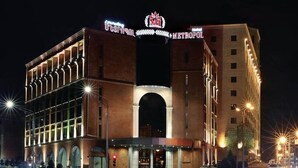 Un hotel con un arco de entrada destacado, un cartel grande encima del arco y una fachada bien iluminada.