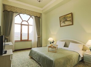 A hotel room with a bed, bedside lamps, a desk with a computer, a window with curtains, and a painting on the wall. - METROPOL HOTEL Yerevan (Yerevan)