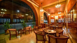Un restaurante con mobiliario de madera, amplios ventanales arqueados y candelabros colgantes.