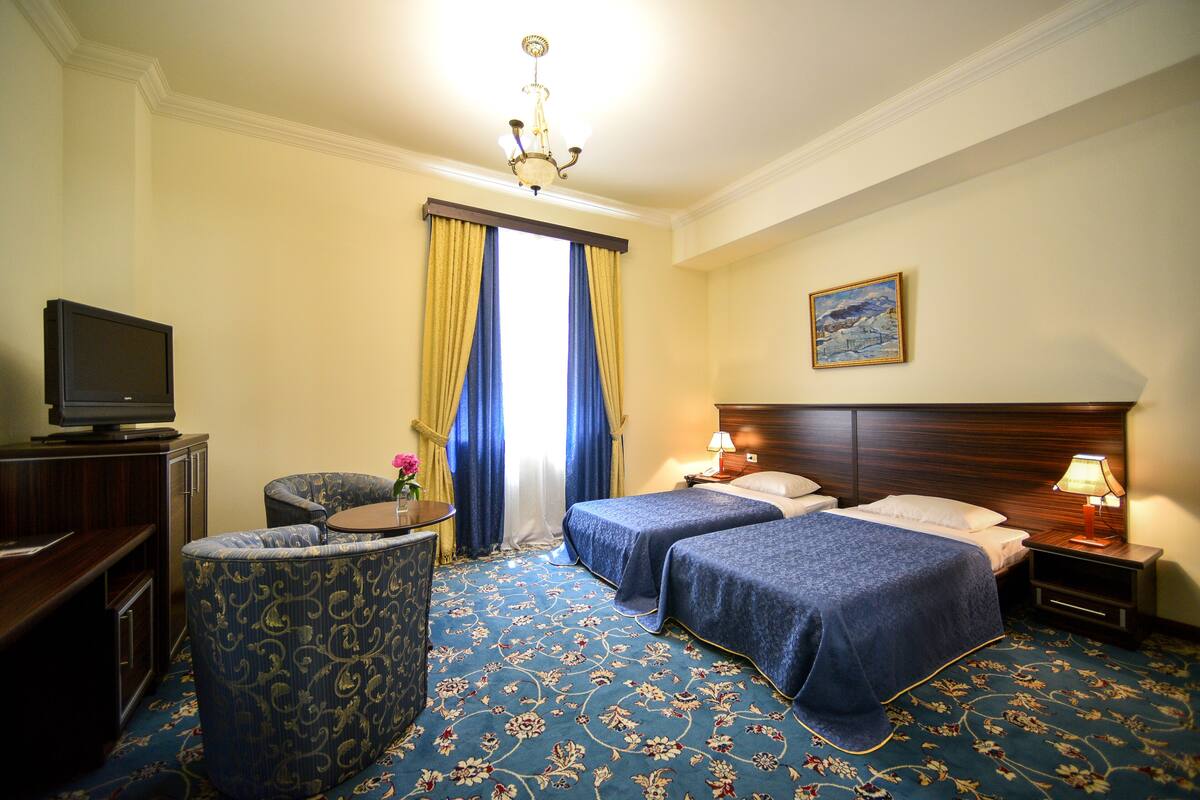 A hotel room with two beds, a TV, a desk, and a chair.