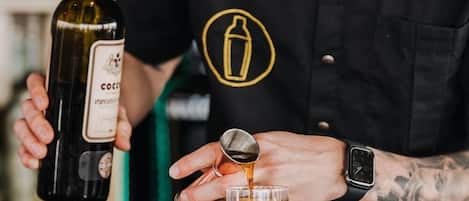 Un barman verse une boisson d’une bouteille dans un verre.