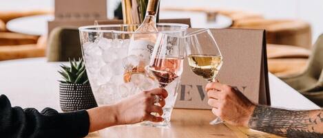 A wooden table with a bottle of champagne and glasses filled with champagne, ice, and water.