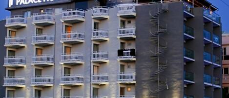 A multi-story hotel with balconies and a cafe bar on the top floor.