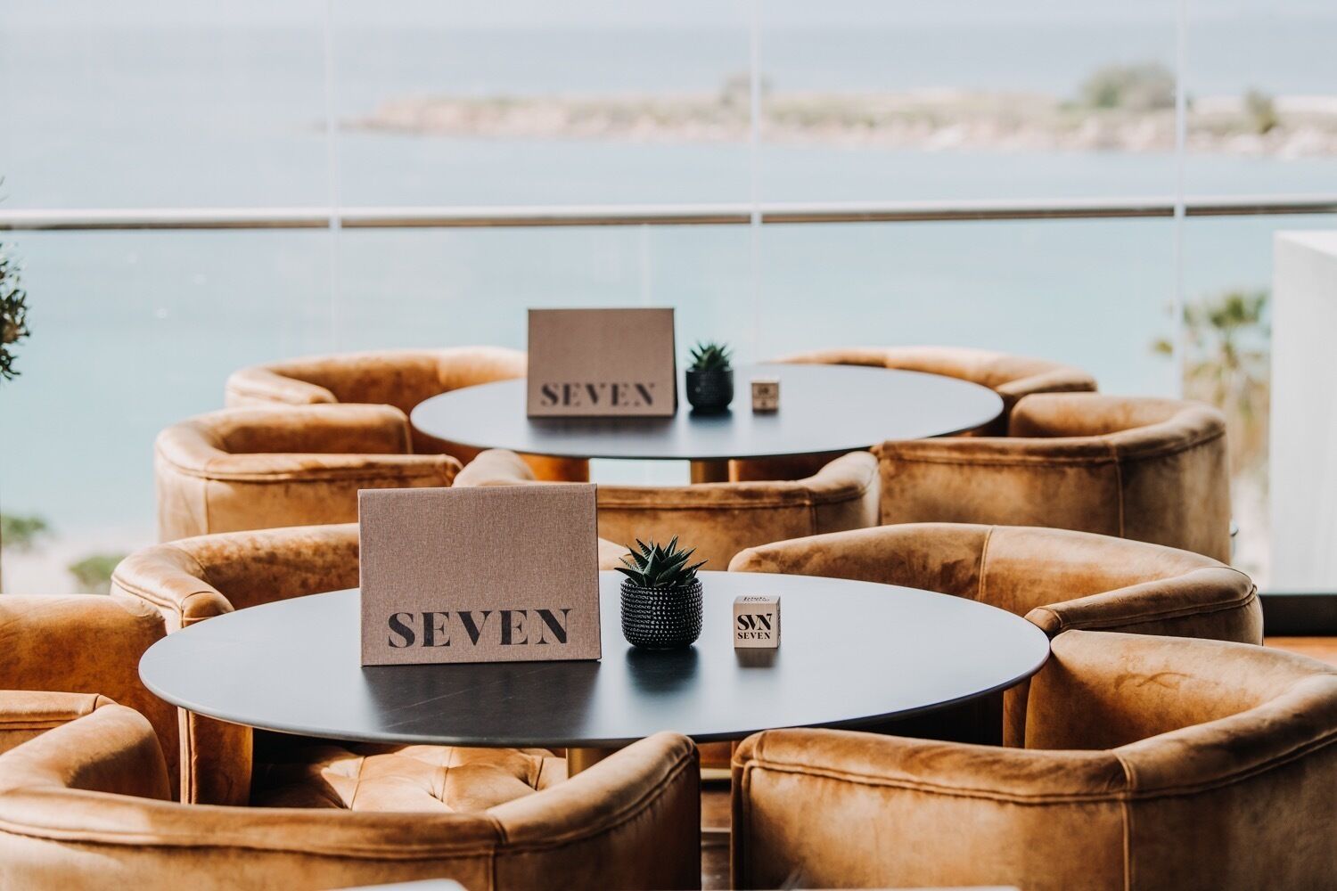 A seating area with round tables and cushioned chairs, each labeled with the number "SEVEN".