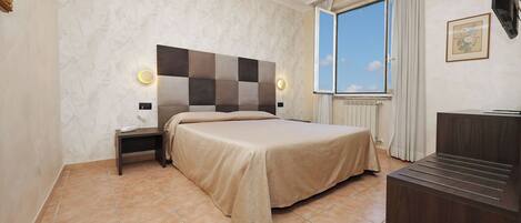 A bedroom with a large bed, a nightstand, a dresser, and a window with curtains.