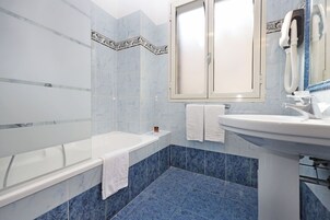 A bathroom with a bathtub, a sink, and a mirror.