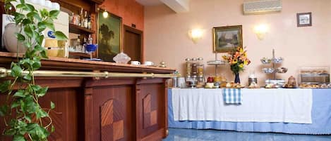 Una hall d'albergo con una reception in legno, un tavolo per il buffet e un condizionatore d'aria a parete.