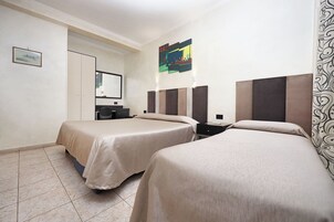 A hotel room with two beds, a desk, a chair, a wardrobe, and a painting on the wall.