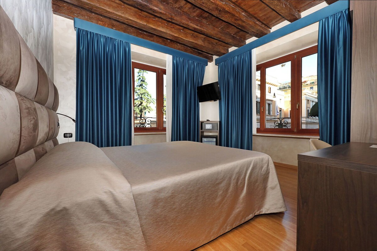 A bedroom with a bed, a desk, and a TV.