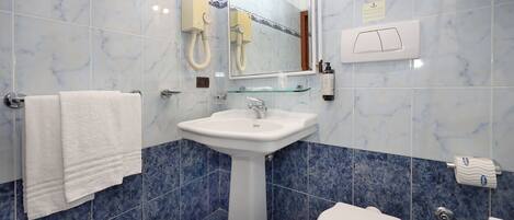 A bathroom with a pedestal sink, a toilet, and a mirror.