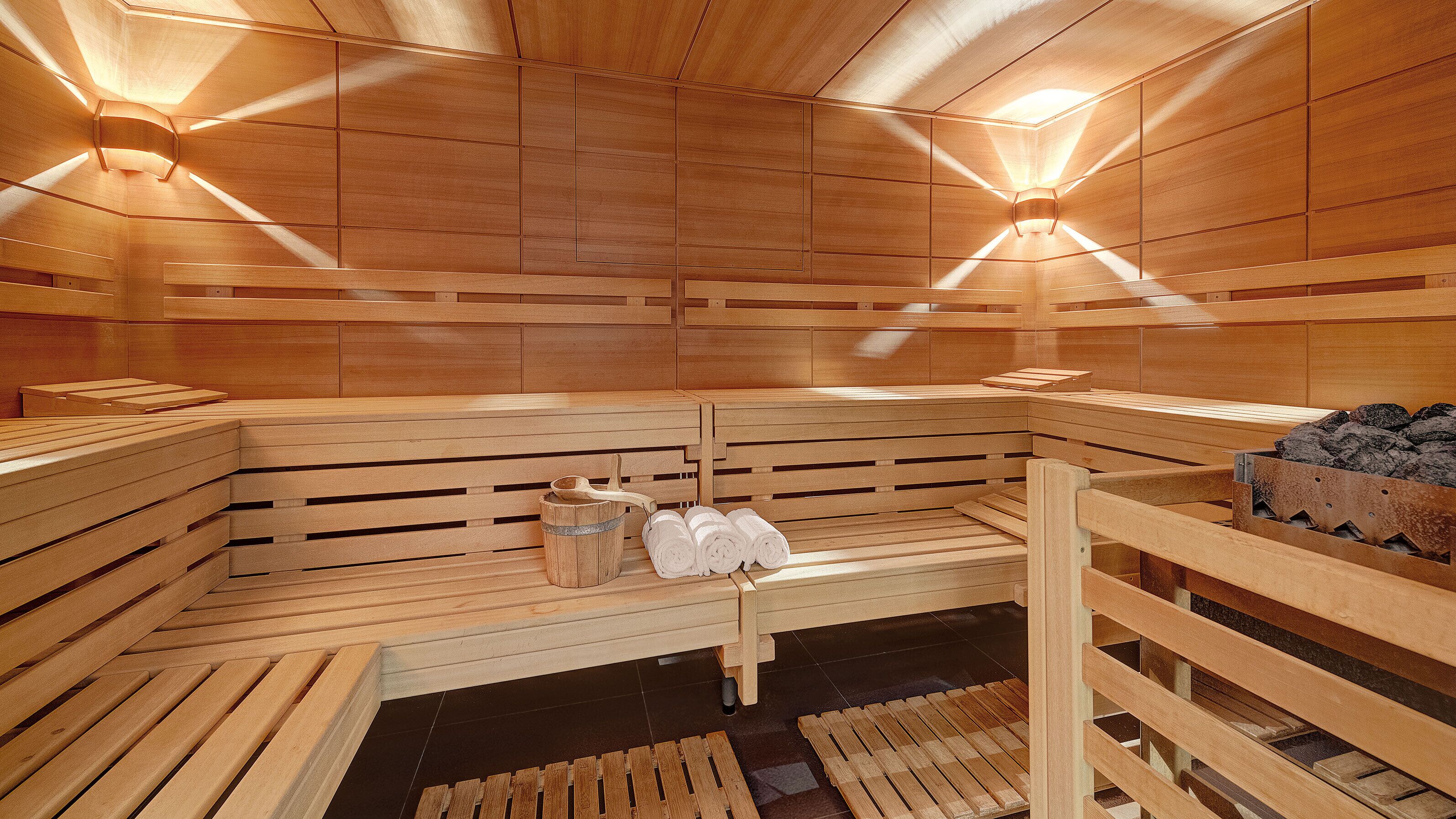Una sauna con bancos de madera, un perchero y un cubo.