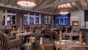 Ein Restaurant mit mehreren Tischen, Stühlen und einem Kamin.