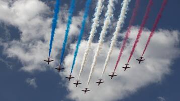 Una formación de aviones volando en un cielo despejado con estelas de humo de colores vivos.