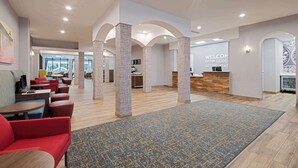 A modern hotel lobby with a reception desk, seating area, and a view of the outdoors. - Hampton Inn Boca Raton-Deerfield Beach (Deerfield Beach)