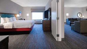 A hotel room with a bed, a TV, a sofa, and a desk. - Hampton Inn Boca Raton-Deerfield Beach (Deerfield Beach)