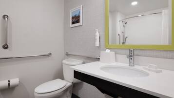 A modern bathroom with a white toilet, a sink, and a mirror with a green frame.