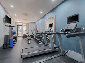 A gym with treadmills, weight machines, and a mirror.