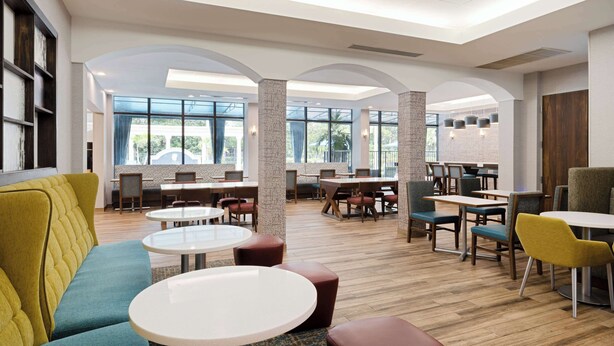 A spacious indoor area with multiple seating arrangements, including sofas and tables, and large windows providing natural light. - Hampton Inn Boca Raton-Deerfield Beach (Deerfield Beach)