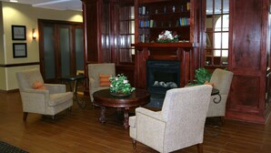 A room with a fireplace, wooden bookshelves, and two armchairs. - Hampton Inn Newberry-Opera House (Newberry)