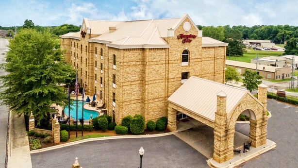 A large hotel with a swimming pool, a covered walkway, and a stone archway. - Hampton Inn Newberry-Opera House (Newberry)