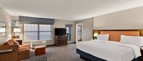 A hotel room with a large bed, a sofa, a TV, and a desk.