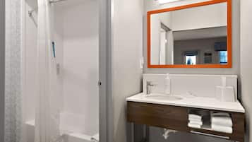 A bathroom with a shower, a sink, a mirror, and a towel rack.