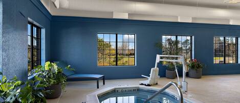 Zona de piscina interior con pared azul, ventanas grandes y plantas en macetas.