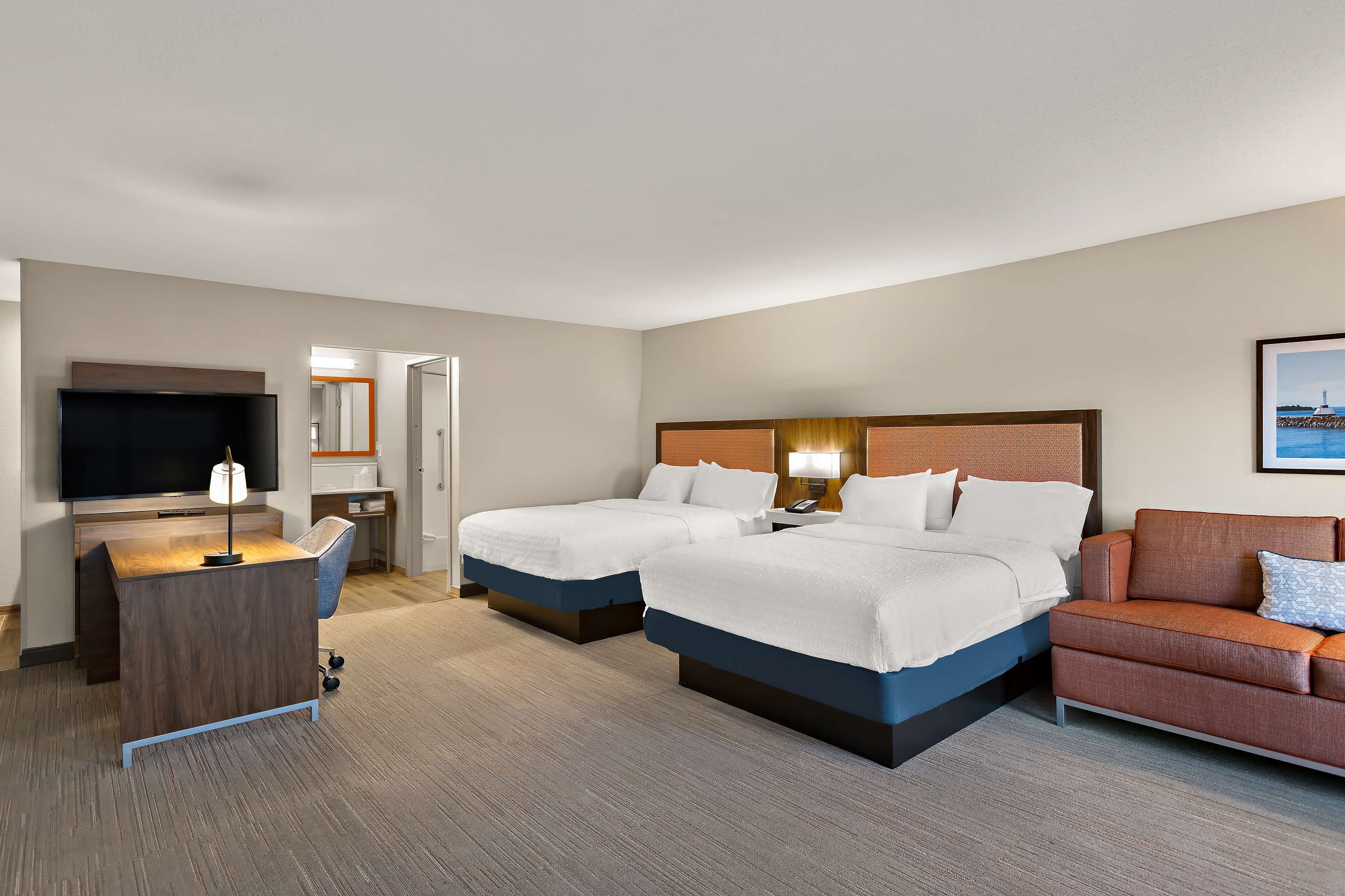 Een hotelkamer met twee bedden, een bureau, een televisie en een bank.