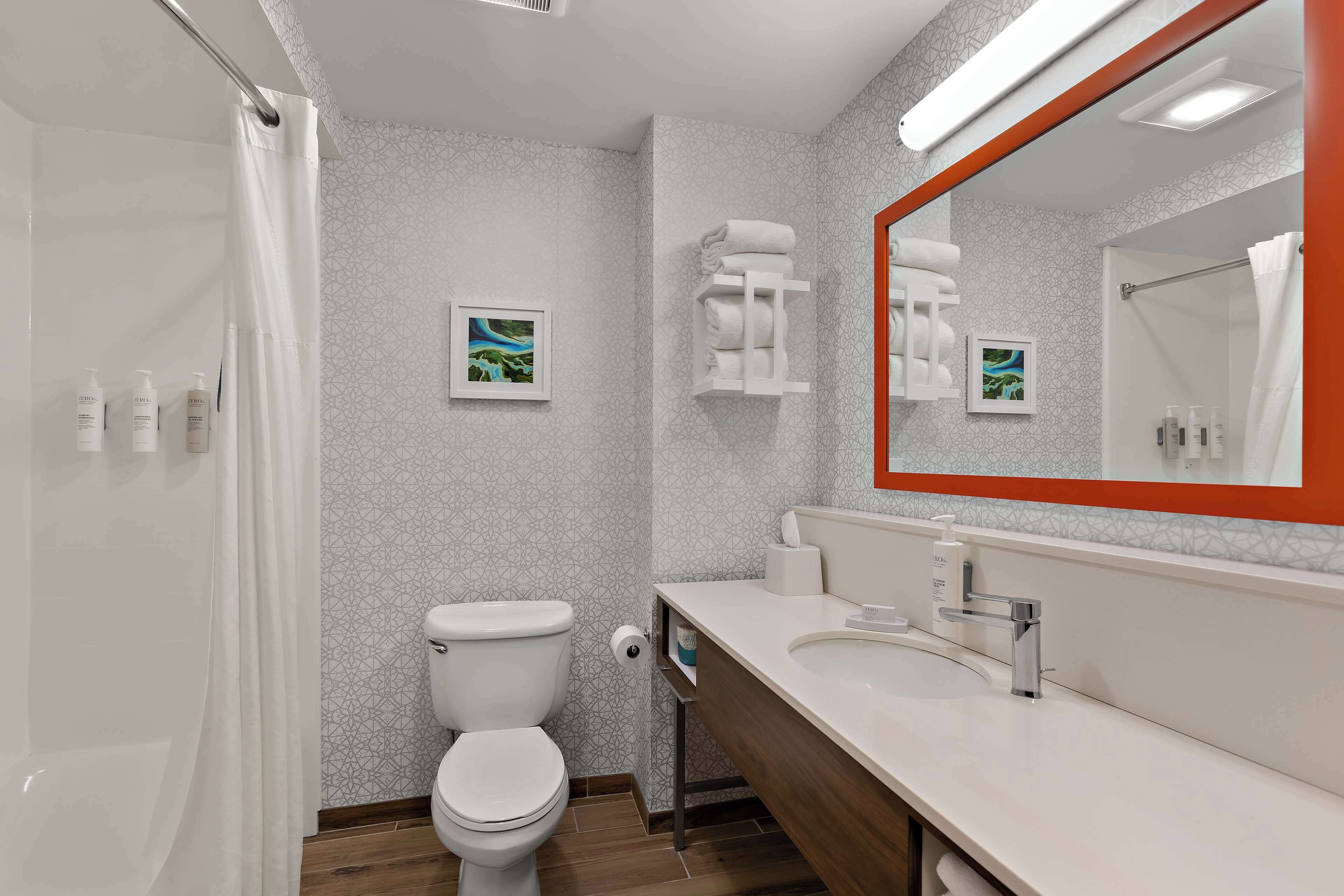 A modern bathroom with a toilet, sink, and shower.