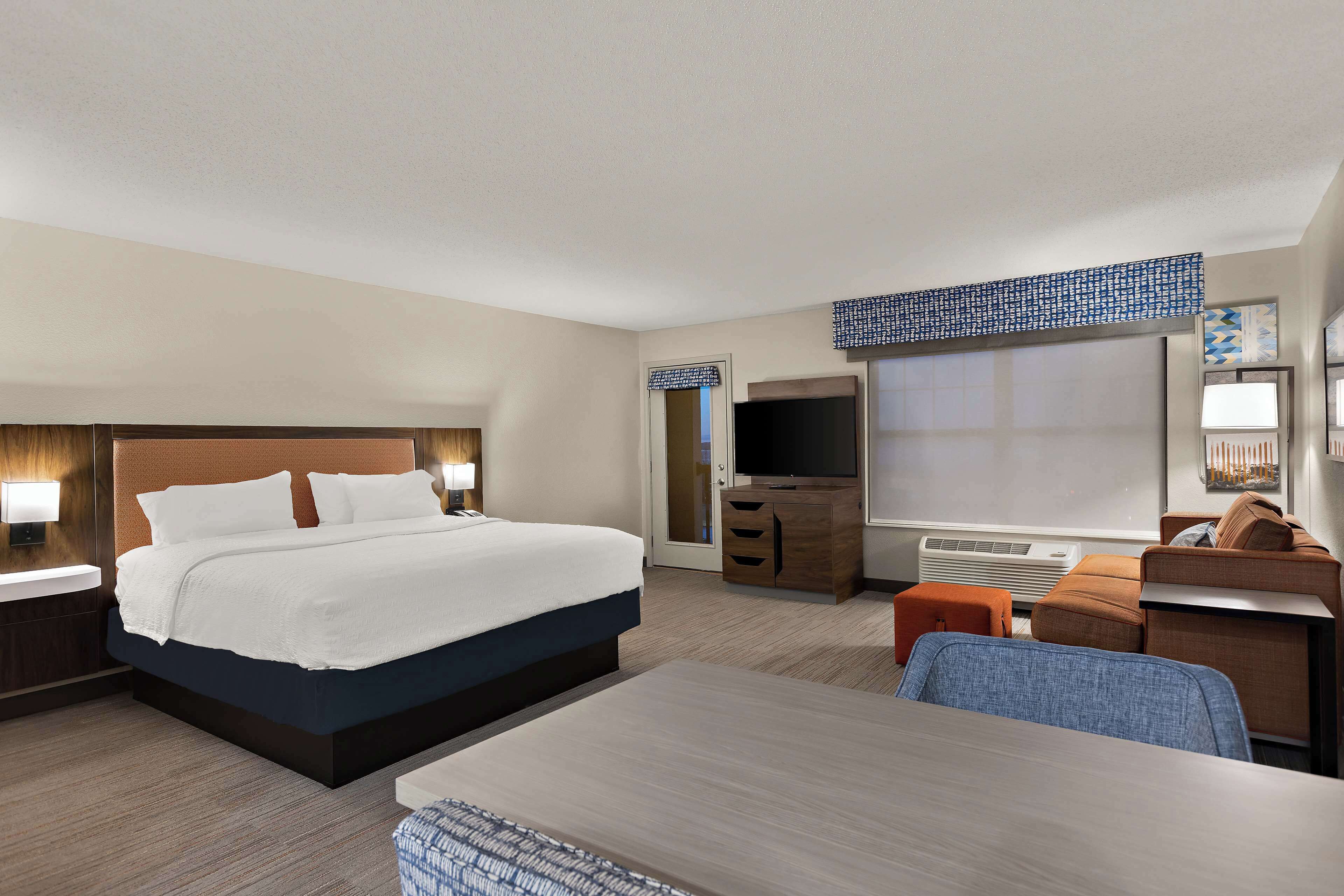 Una habitación de hotel con una cama grande, un escritorio, una silla, un televisor y un armario.