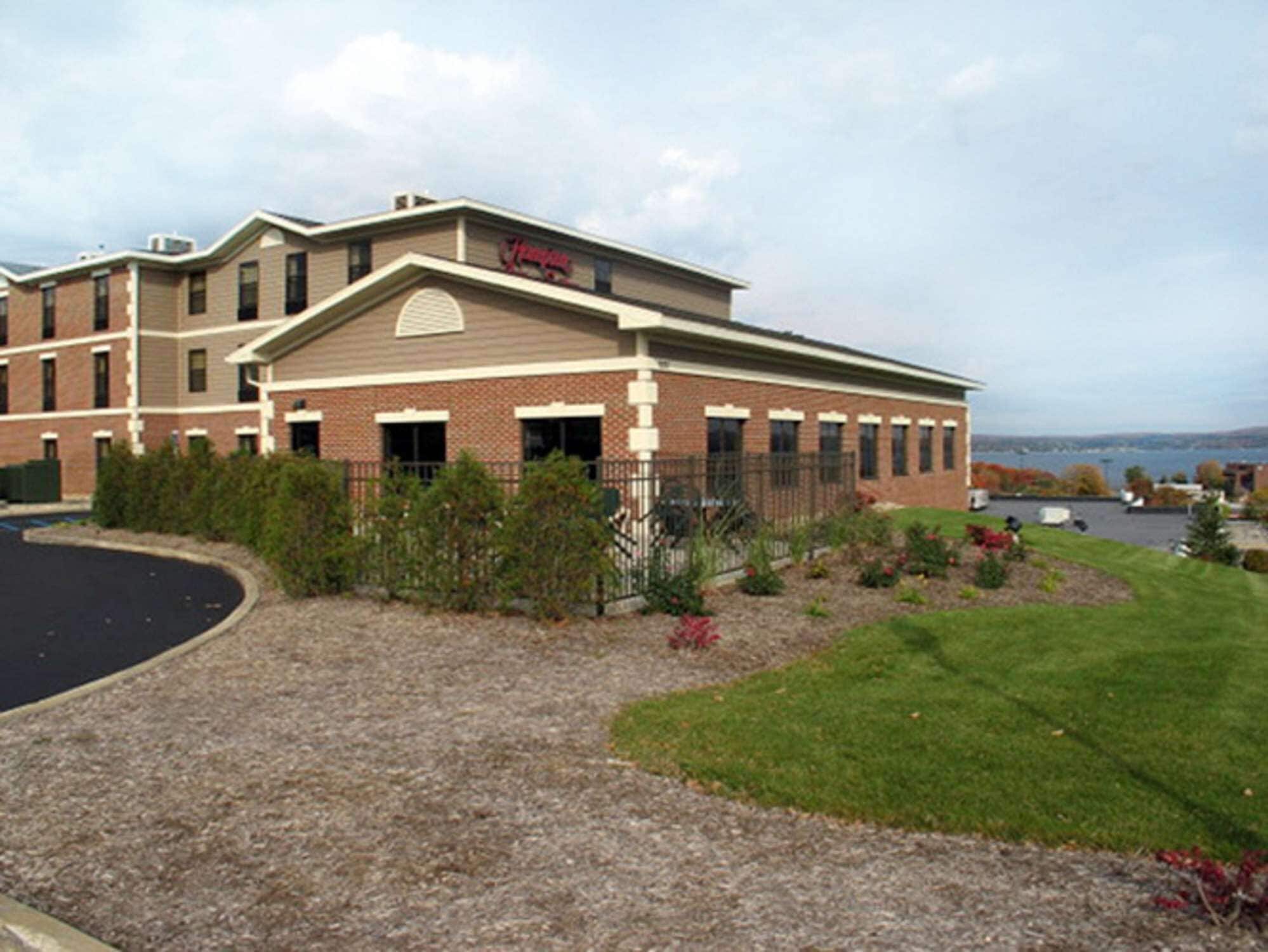 A hotel with a brick facade, a large entrance, and a view of the water in the background.