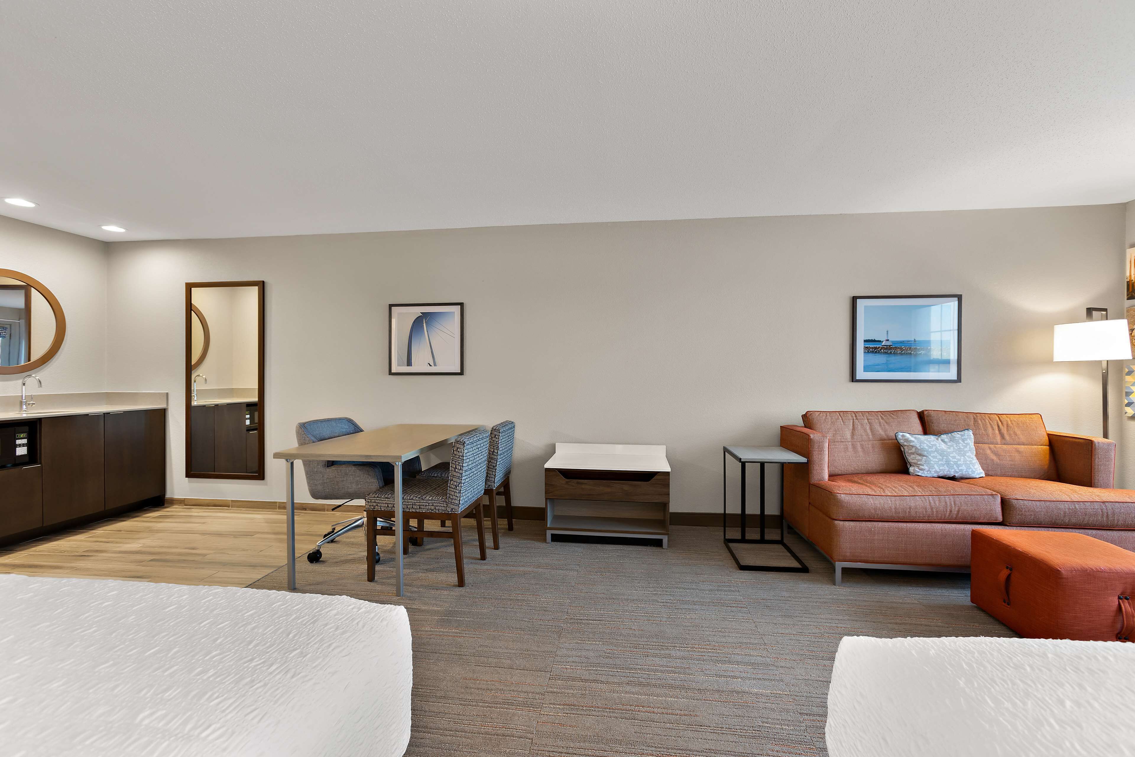 Une chambre d’hôtel comprenant un lit, un bureau avec une chaise, un canapé, une petite table et une lampe.