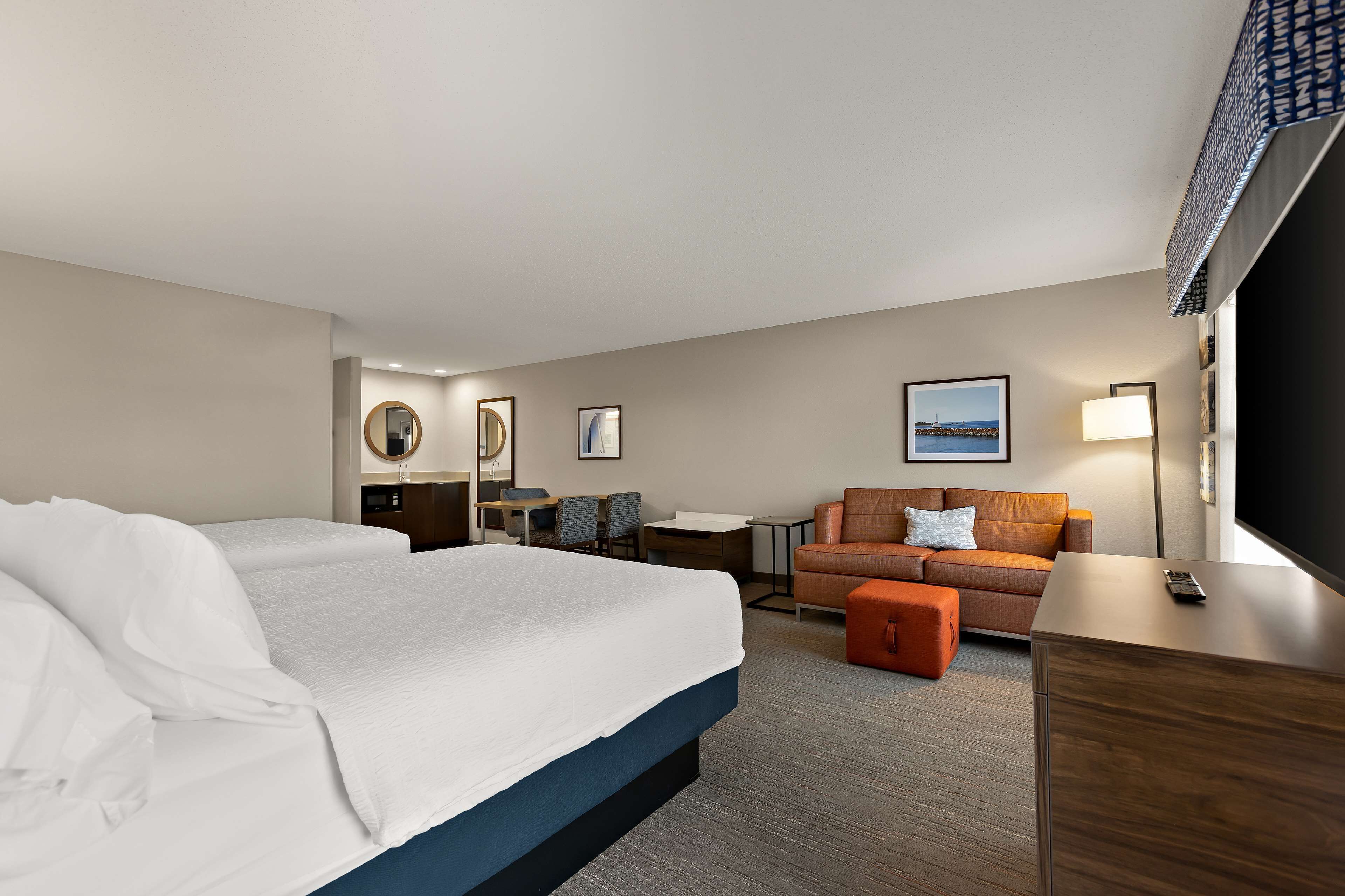 A hotel room with a large bed, a sofa, a desk, and a TV.